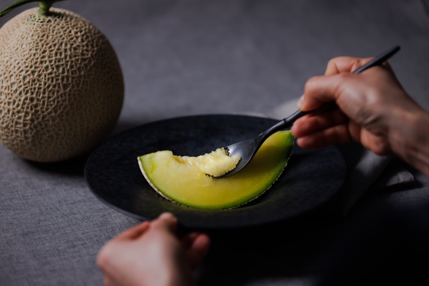 A spoonful of ripe Crown Melon, shared by hand